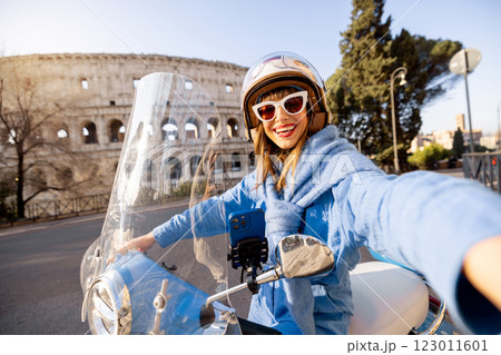 Cheerful Woman Taking a Selfie on a Scooter Near the Colosseum in Rome 123011601