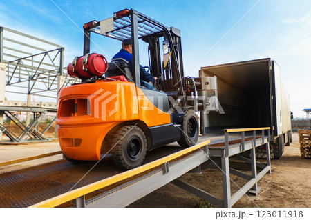 Forklift is putting cargo from warehouse to truck outdoors 123011918