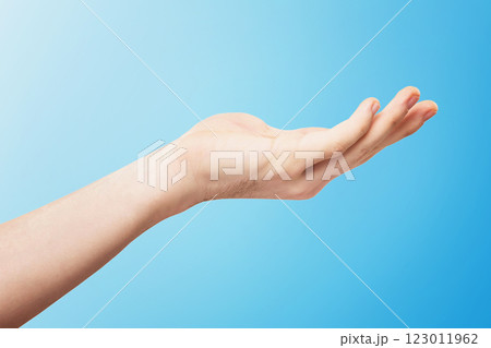 Closeup empty male hand making holding gesture isolated at blue background. Closeup empty male hand making holding gesture isolated at blue background. 123011962