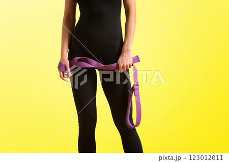 Slim athlete woman is holding trx straps for fitness training at isolated yelow background. 123012011