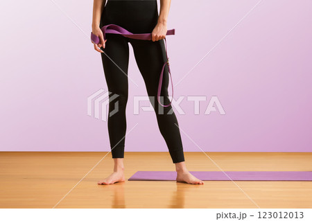 Slim athlete woman is holding trx straps for fitness training at isolated purple background. 123012013