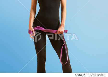 Slim athlete woman is holding trx straps for fitness training at isolated blue background. 123012016