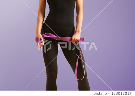 Slim athlete woman is holding trx straps for fitness training at isolated background. 123012017