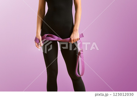 Slim athlete woman is holding trx straps for fitness training at isolated purple background. 123012030