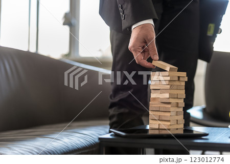Businessman standing in office building a tower of stacked blocks 123012774