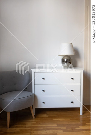 Minimalist interior with white dresser and gray chair 123012972