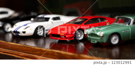 Collection of toy cars displayed on wooden shelf 123012991