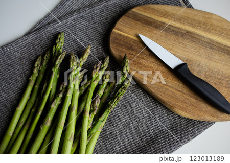 Raw green asparagus with kitchen towel, knife and cutting board 123013189