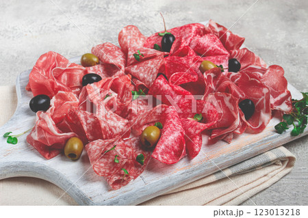 Assorted, meat appetizer, prosciutto, salami and ham, with olives , on a wooden white board, light background, breakfast, top view, close-up, no people Assorted, meat appetizer, prosciutto, salami and ham, with olives , on a wooden white board, light background, breakfast, top view, close-up, no people 123013218