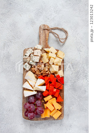 Assorted cheese on a wooden board, with grapes and walnuts, appetizer, no people. 123013242