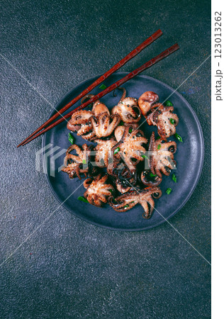 Grilled baby octopus, served with chopsticks, on a black plate, homemade, no people, 123013262