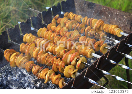 Potato skewers with bacon. Marinated shashlik preparing on barbecue grill over charcoal Potato skewers with bacon. Marinated shashlik preparing on barbecue grill over charcoal 123013573