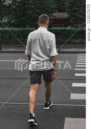 A man crossing the street in casual attire, embodying a sense of style and freedom A man crossing the street in casual attire, embodying a sense of style and freedom 123015078
