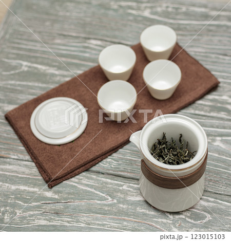 An Elegant Tea Set complete with Beautiful Cups and Fresh Leaves displayed on a Wooden Surface 123015103
