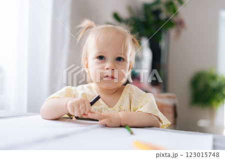 Portrait of cute child girl drawing with colored pencils on sketchbook, sitting at table, enjoying creative playtime in cozy home environment. Concept of early childhood development Portrait of cute child girl drawing with colored pencils on sketchbook, sitting at table, enjoying creative playtime in cozy home environment. Concept of early childhood development 123015748