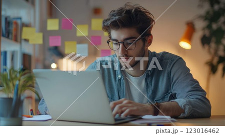 Young man working on a laptop at a desk. 123016462