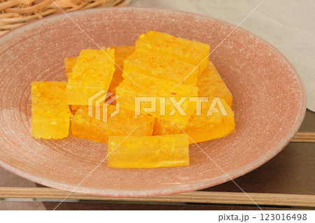 Marmalade in a plate in garden table. Sweet orange dessert for holiday. Homemade fruit candies. 123016498