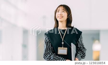 ノートパソコンを持って歩く若い女性・ビジネスウーマン ノートパソコンを持って歩く若い女性・ビジネスウーマン 123018854