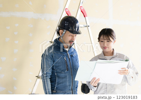 デニムの作業着の男性と設計図を持つ作業着の女性 現場の確認 デニムの作業着の男性と設計図を持つ作業着の女性 現場の確認 123019183