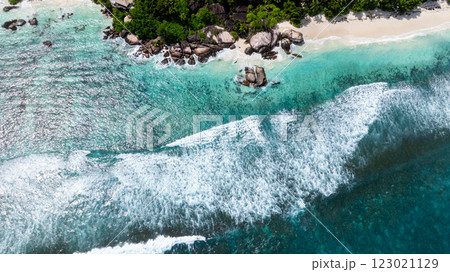 Turquoise waves crash against rocks along a scenic coast lined with lush vegetation. Seychelles, Mahe. 123021129