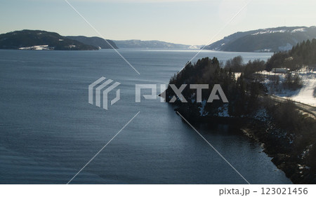 A serene winter landscape featuring a deep blue fjord A serene winter landscape featuring a deep blue fjord 123021456