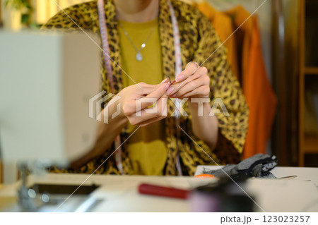 Close up of fashion designer threading needle, preparing for sewing work 123023257