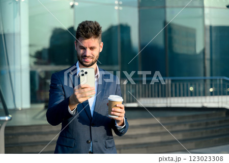 Successful caucasian businessman using smartphone outside a modern office building Successful caucasian businessman using smartphone outside a modern office building 123023308
