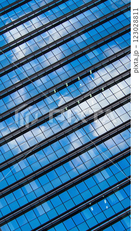 a dynamic reflection of the sky and clouds on the sleek glass facade of a modern building. The diagonal orientation adds a sense of movement and contemporary style to the composition. 123028811