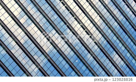 A dynamic perspective of a glass facade reflecting the sky. The diagonal lines and repeating patterns create a striking geometric composition. 123028816