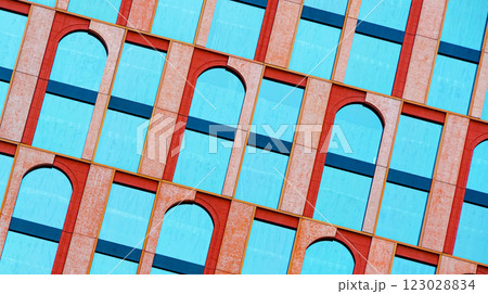 The geometric facade blends symmetry and contrast, with vivid blue windows framed by textured red arches. The tilted angle enhances the rhythmic pattern of repetition. The geometric facade blends symmetry and contrast, with vivid blue windows framed by textured red arches. The tilted angle enhances the rhythmic pattern of repetition. 123028834
