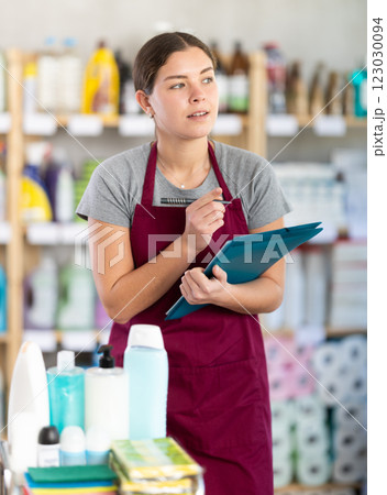 Female supervisor taking notes during inventory in cleaning and hygiene products store 123030094