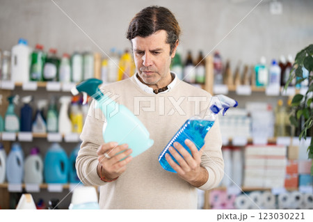 man chooses a spray to clean surfaces 123030221