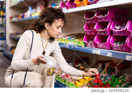 Woman selects required number of sweets and stow m in disposable bag in Russian product store 123030224