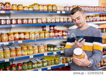 Adult man with mobile phone chooses sauerkraut 123030258