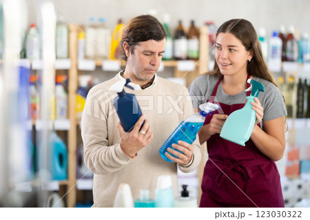 Female consultant helps man buyer choose glass cleaner spray 123030322