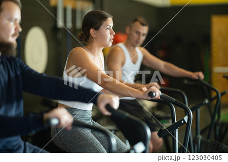 Sportive young girl doing air bike exercises in well-equipped gym 123030405
