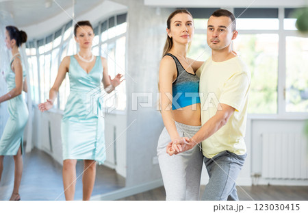 Couple in comfortable sports clothes waltz dancing during individual lesson Couple in comfortable sports clothes waltz dancing during individual lesson 123030415