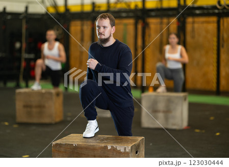 Young bearded man stepping up onto box during cross training 123030444
