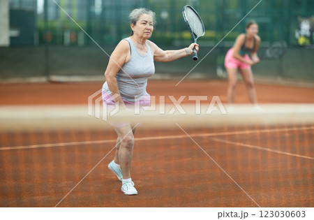 Young and elderly women playing doubles tennis Young and elderly women playing doubles tennis 123030603