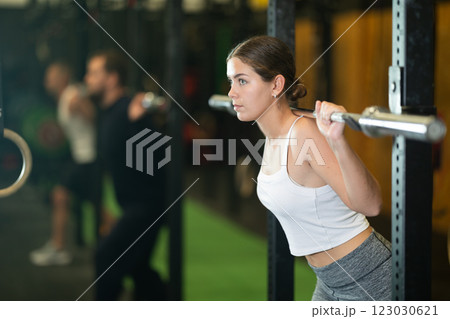 Young woman performing exercises with barbell during intense training Young woman performing exercises with barbell during intense training 123030621