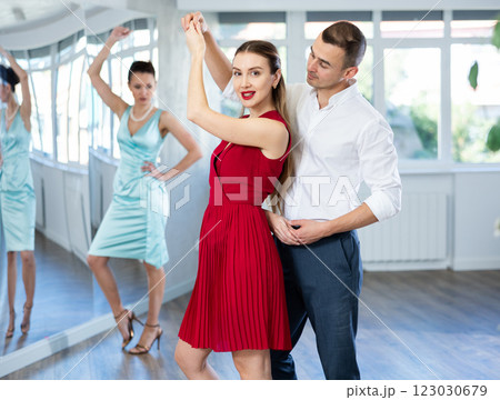 Woman in red dancing passionate bachata with man at dance class 123030679