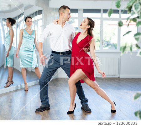 Couple in stage costumes learns tango dancing during individual lesson 123030835