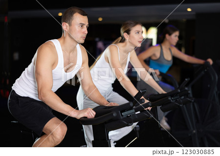 Man performs exercises with stationary bicycle in gym 123030885
