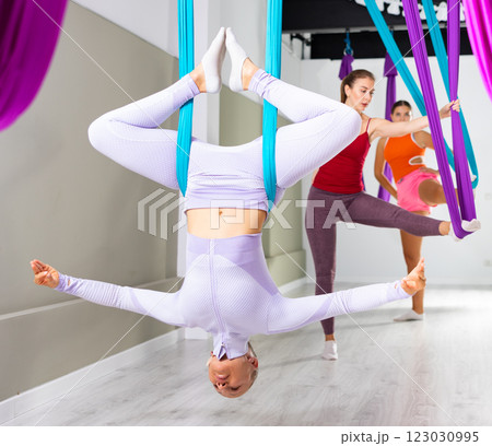 Woman doing inverted bound angle pose in hanging hammock with fingers in mudra Woman doing inverted bound angle pose in hanging hammock with fingers in mudra 123030995