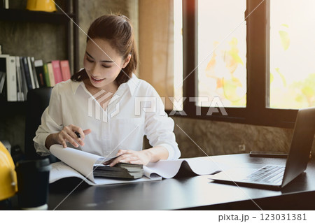 A professional, successful Asian female architect boss is working on a project at her desk. 123031381