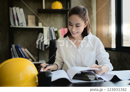 A professional, successful Asian female architect boss is working on a project at her desk. 123031382