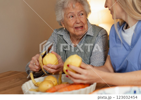 Portrait of elderly companion assistant and senior woman peeling potatoes. Home health care services. 123032454