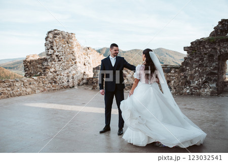 Bride and groom dancing, looking at each other. Wedding couple standing outside near ruins. Bride and groom dancing, looking at each other. Wedding couple standing outside near ruins. 123032541