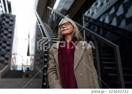 An older woman dressed warmly stands confidently on urban stairs enjoying a moment of reflection in An older woman dressed warmly stands confidently on urban stairs enjoying a moment of reflection in 123032722