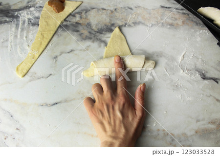 A woman's hand twists raw dough into a croissant 123033528